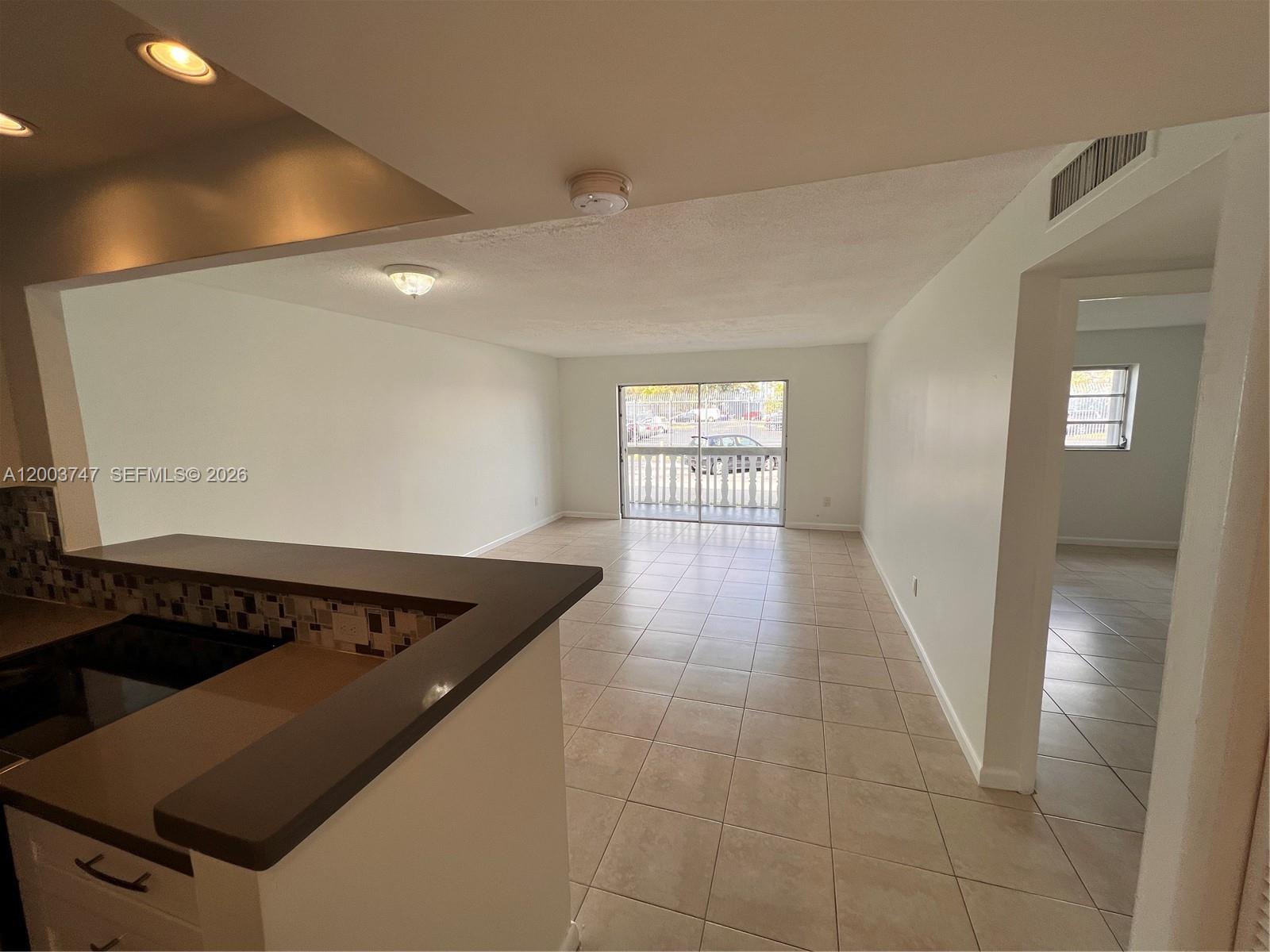 An open-concept living area features tile flooring, a breakfast bar, and sliding glass balcony doors — 15221 NE 6th Ave # A104, Miami FL 33162, MIAMI, FL