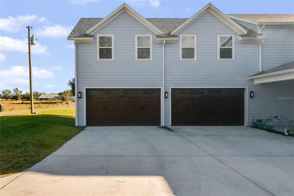 The exterior of a two-story duplex features light blue siding and two dark wood garage doors — 12752 S LAKE SAWYER LANE, WINDERMERE, FL
