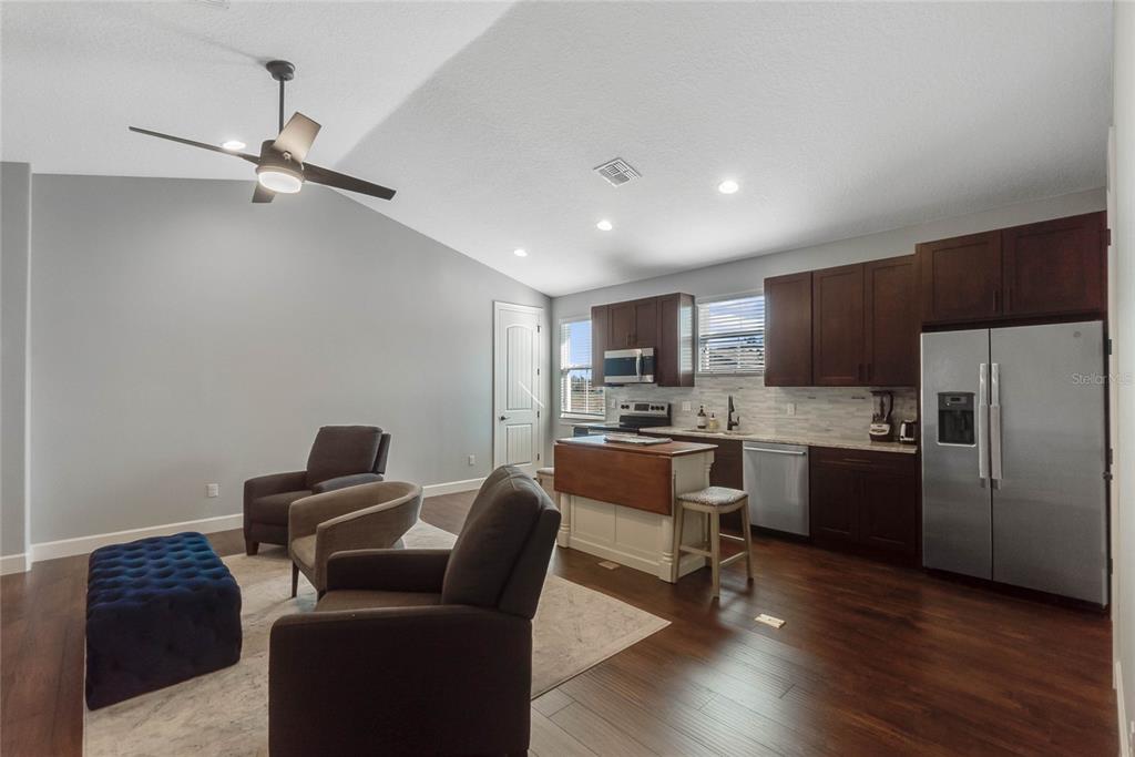 A kitchen with dark wood cabinets and stainless steel appliances opens to a living area — 12752 S LAKE SAWYER LANE, WINDERMERE, FL