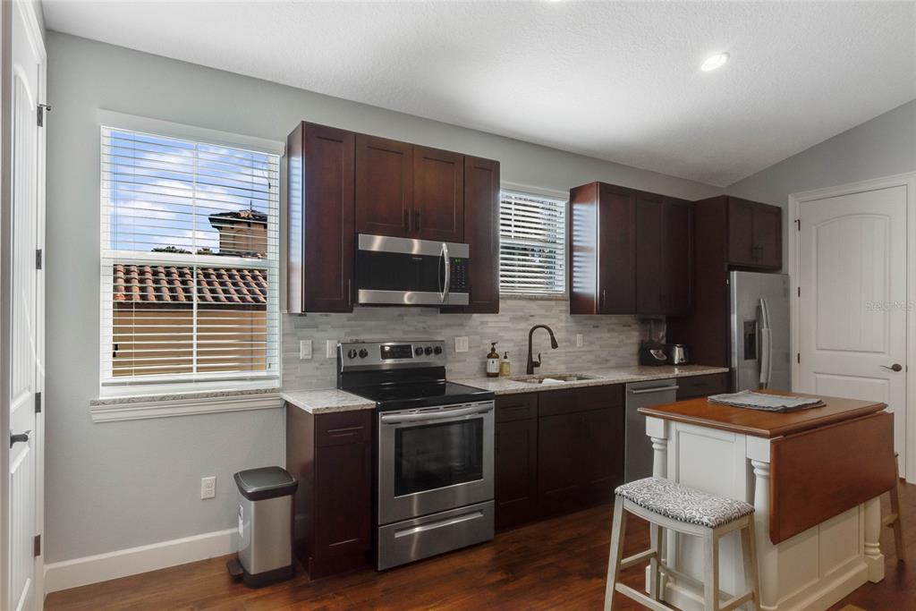 A kitchen features dark wood cabinets, stainless steel appliances, a kitchen island, and light countertops — 12752 S LAKE SAWYER LANE, WINDERMERE, FL