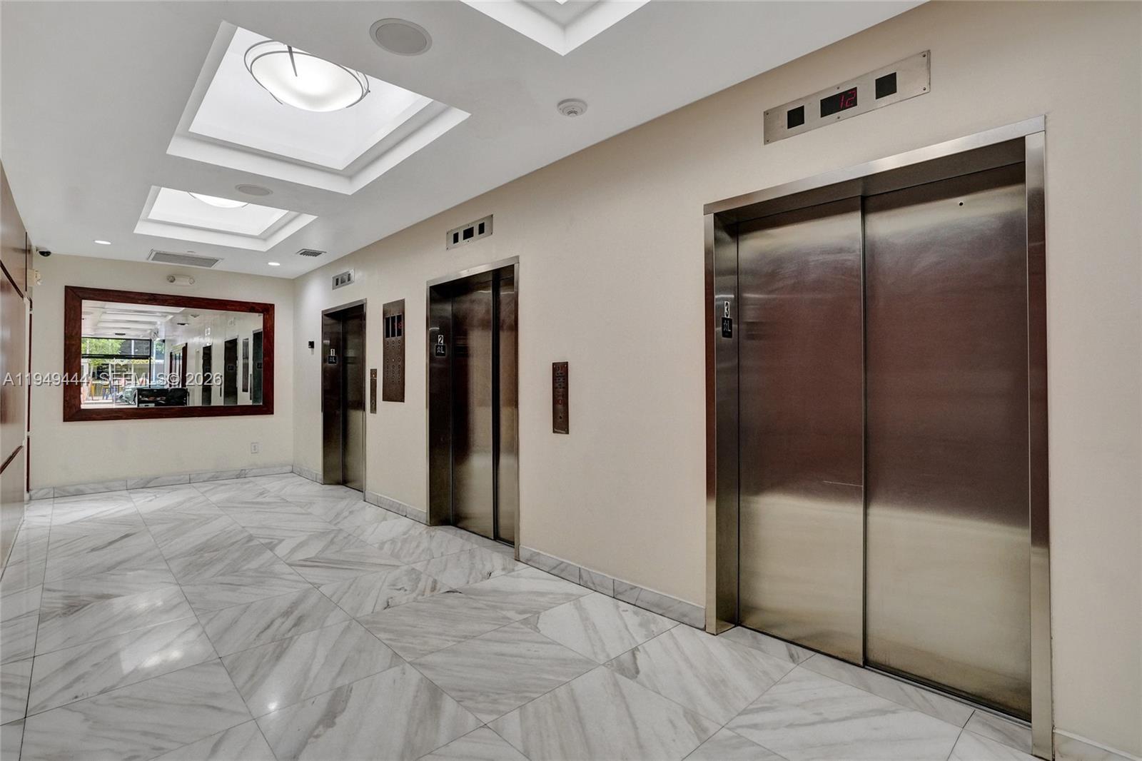 An elevator lobby features marble floors, recessed ceiling lights, and stainless steel elevator doors — 168 SE 1st St # 1200, Miami FL 33131, MIAMI, FL