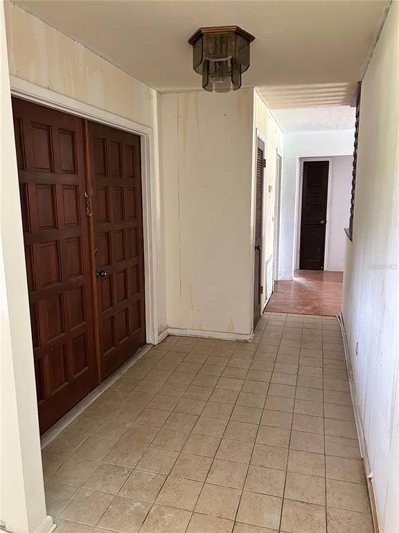 A kitchen with a breakfast bar and wooden spindles overlooks a tiled hallway and living area — 7250 WOODBROOK DR, TAMPA, FL