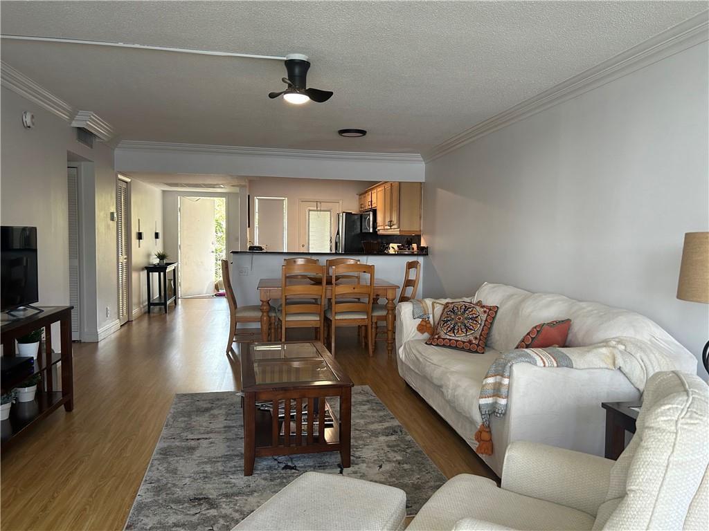 A living room with wood flooring, a white sofa, and an adjacent dining area — 3150 N Course Lane # 207, Pompano Beach FL 33069, POMPANO BEACH, FL