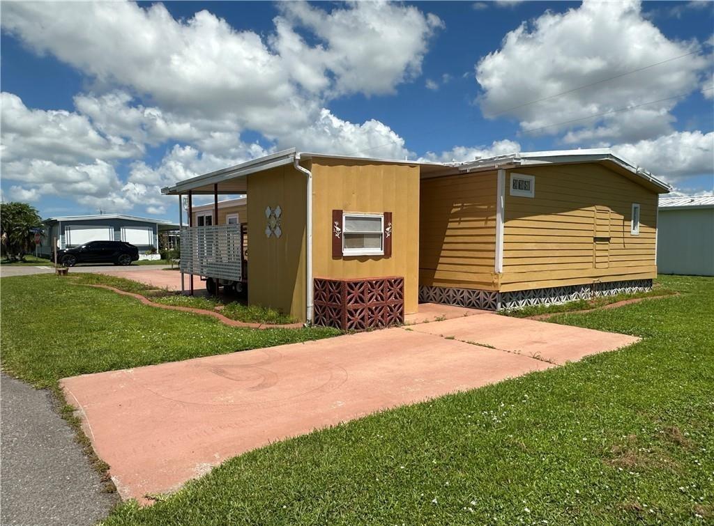 A yellow mobile home with a covered porch and a red concrete driveway — 14700 Patrick Henry Road # 1, FL 33917, FL