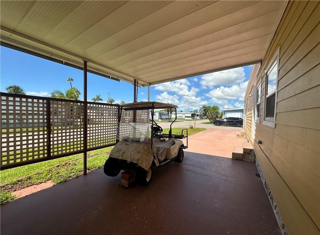 A golf cart sits under a covered carport next to a yellow mobile home — 14700 Patrick Henry Road # 1, FL 33917, FL