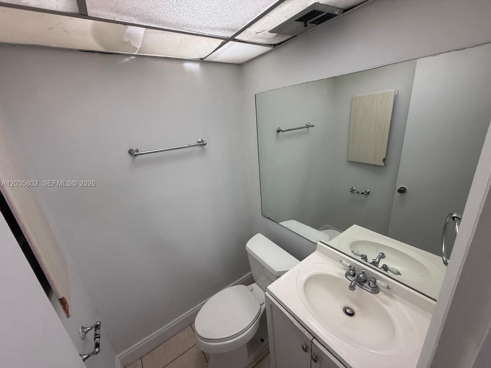 A small bathroom features a white vanity, a toilet, and a large wall mirror — 6675 W 4th Ave # 402, Hialeah FL 33012, HIALEAH, FL