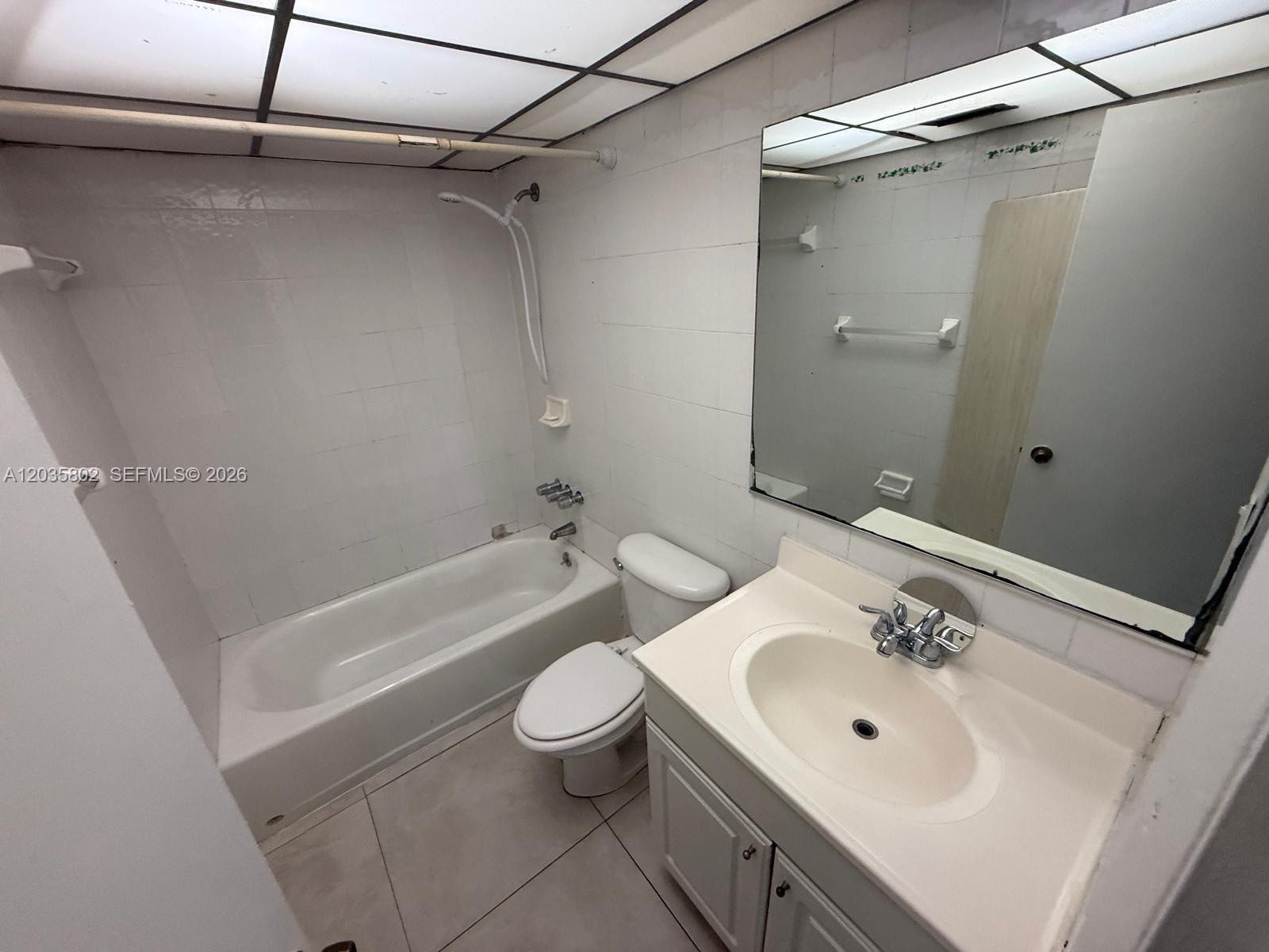 A bathroom features a white vanity, a toilet, and a bathtub with a shower head — 6675 W 4th Ave # 402, Hialeah FL 33012, HIALEAH, FL