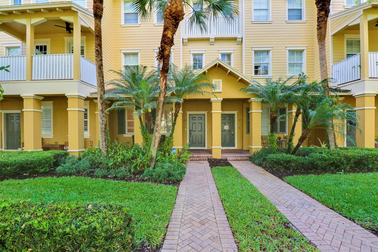 A yellow multi-story apartment building with a brick walkway leading to two front doors — 123 E Thatch Palm Circle, Jupiter FL 33458, JUPITER, FL