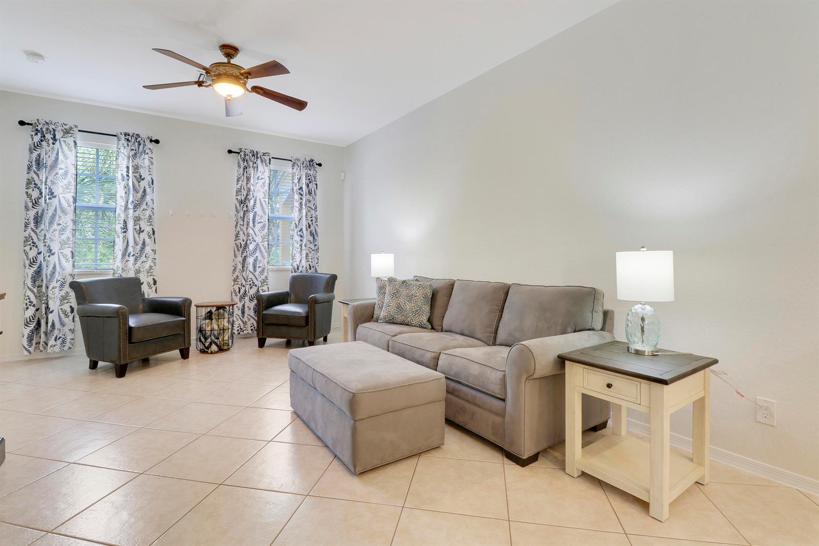 A living room features a grey sofa, matching ottoman, two armchairs, and tile flooring — 123 E Thatch Palm Circle, Jupiter FL 33458, JUPITER, FL