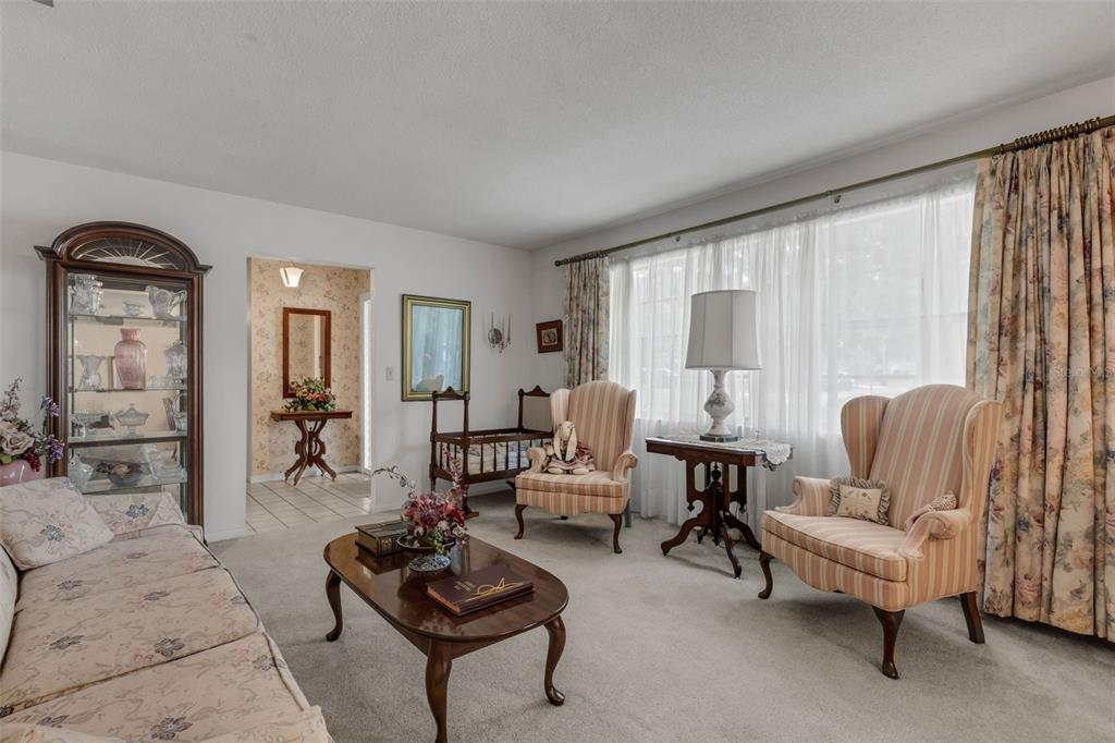 A living room features a sofa, two striped armchairs, a coffee table, and a curio cabinet — 402 ABERDEEN COURT N, LAKELAND, FL
