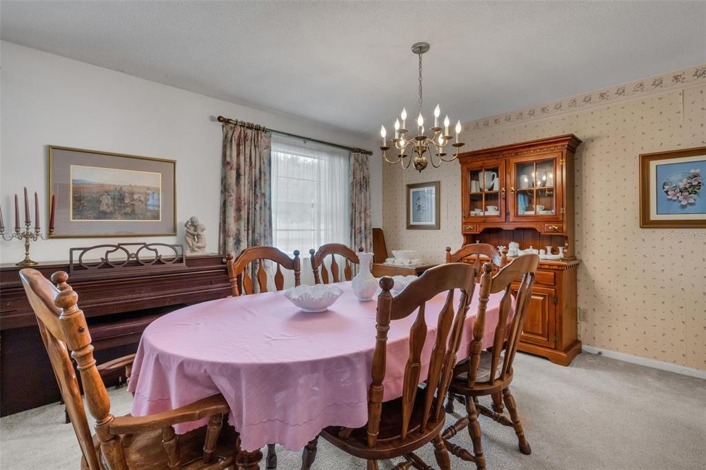 A dining room features a wooden table with a pink cloth, chairs, and a hutch — 402 ABERDEEN COURT N, LAKELAND, FL