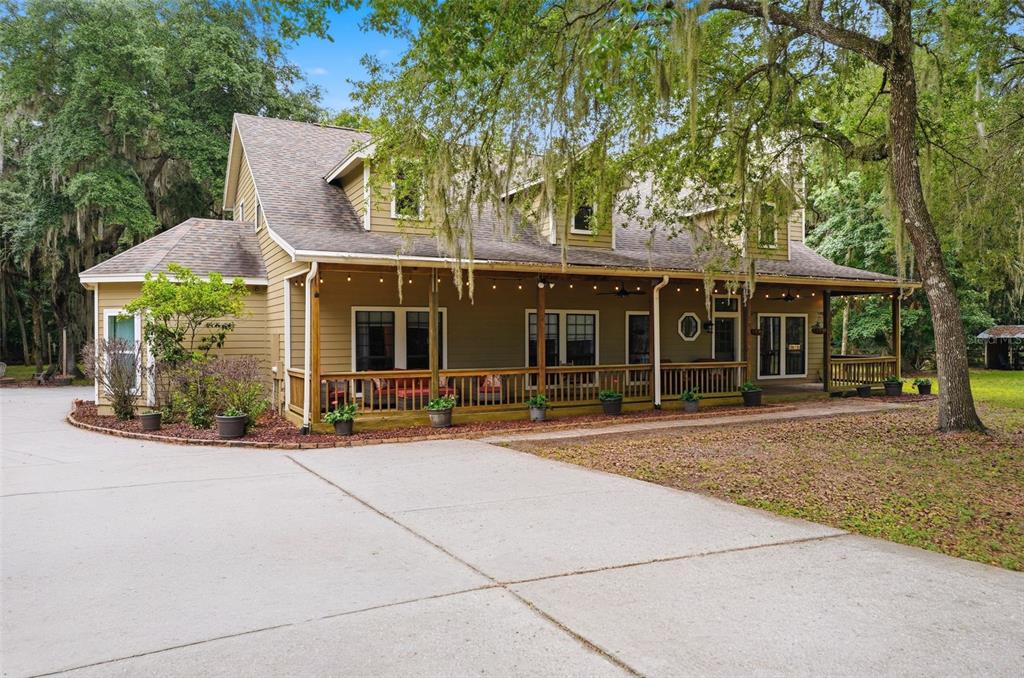 A concrete driveway leads to a two-story house surrounded by mature trees and lush landscaping — 381 N JUNGLE ROAD, GENEVA, FL