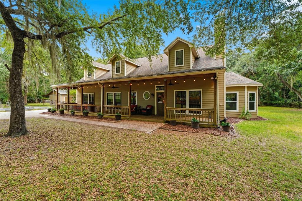 A two-story tan house with a large front porch and a concrete driveway — 381 N JUNGLE ROAD, GENEVA, FL