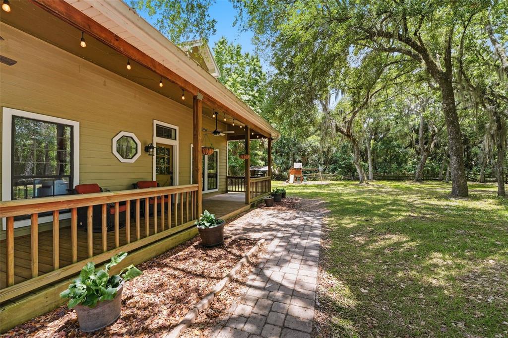 A two-story house with tan siding, a wraparound porch, and dormer windows in a wooded yard — 381 N JUNGLE ROAD, GENEVA, FL