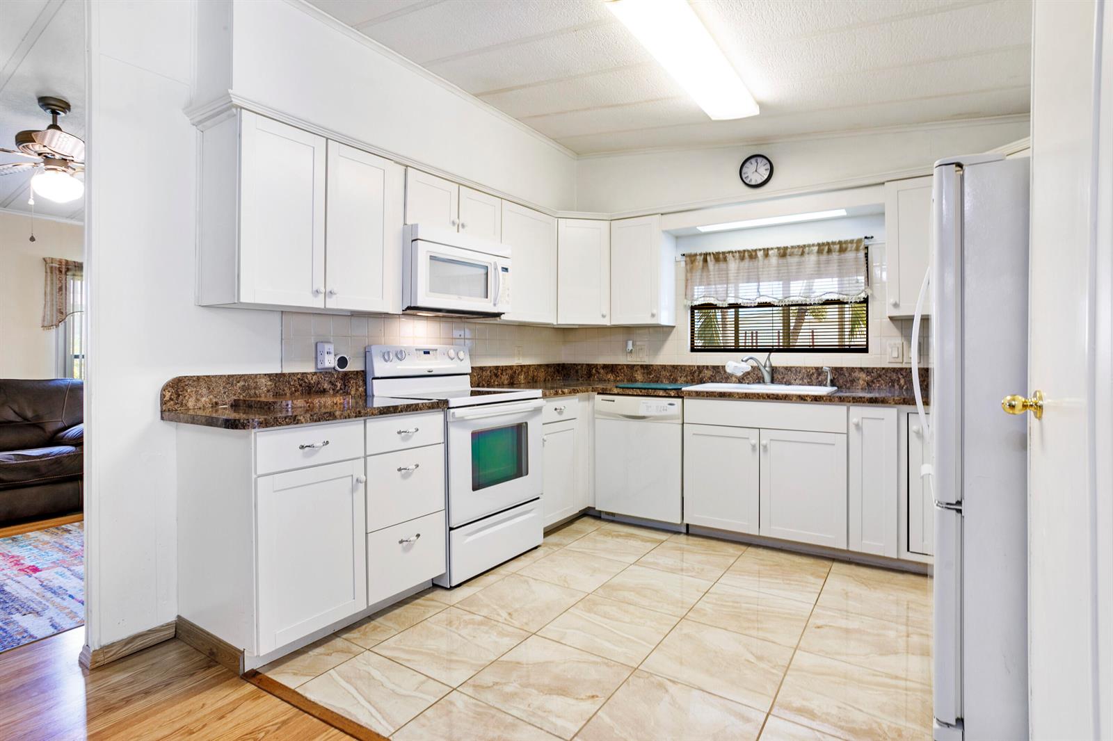 A kitchen with white cabinets, brown countertops, white appliances, and light-colored tile flooring — 48014 Jaruco Bay, Boynton Beach FL 33436, BOYNTON BEACH, FL