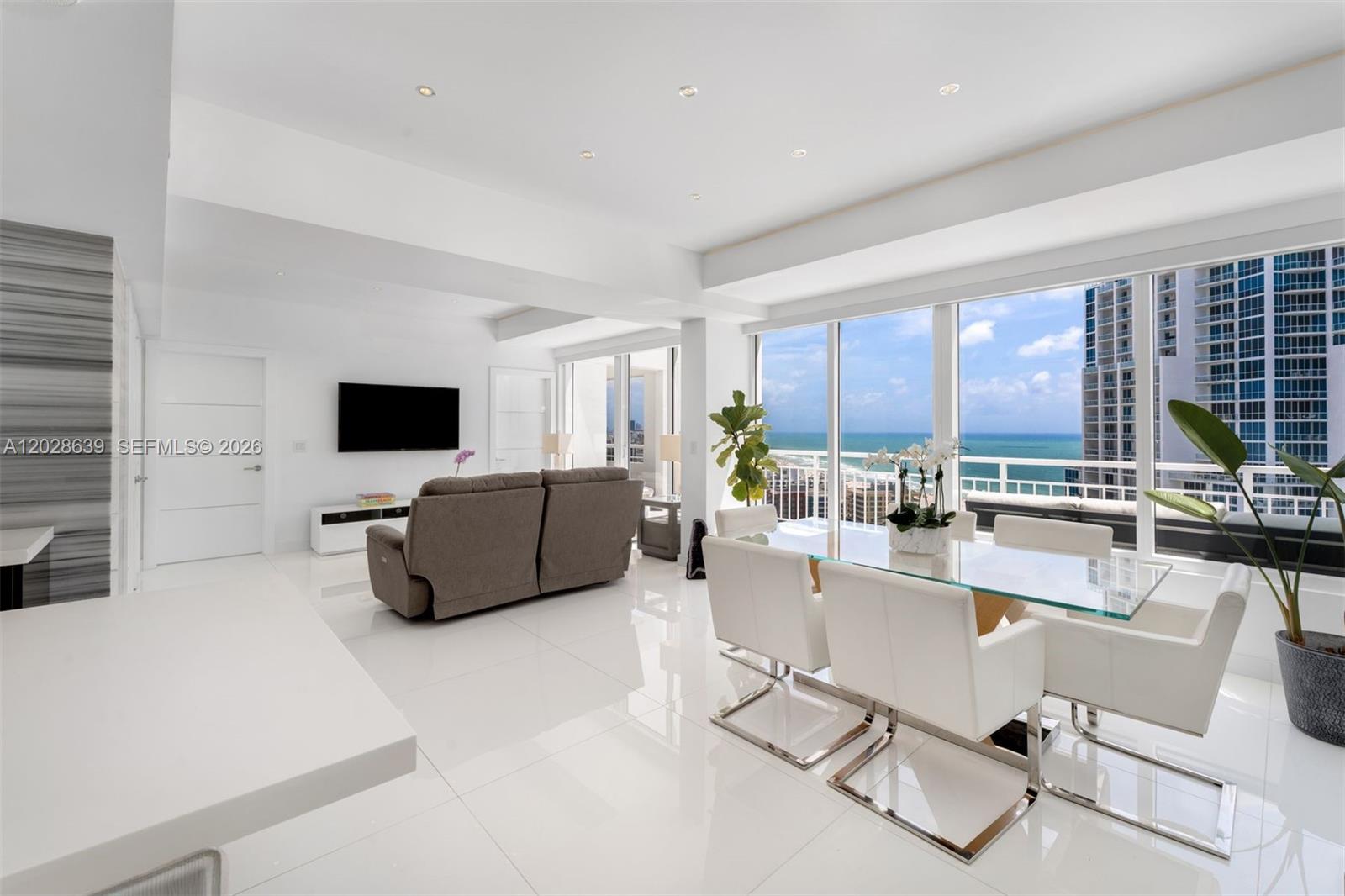 A bright, modern living and dining area features white tile floors and floor-to-ceiling ocean views — 400 S Pointe Dr, Miami Beach FL 33139, MIAMI BEACH, FL
