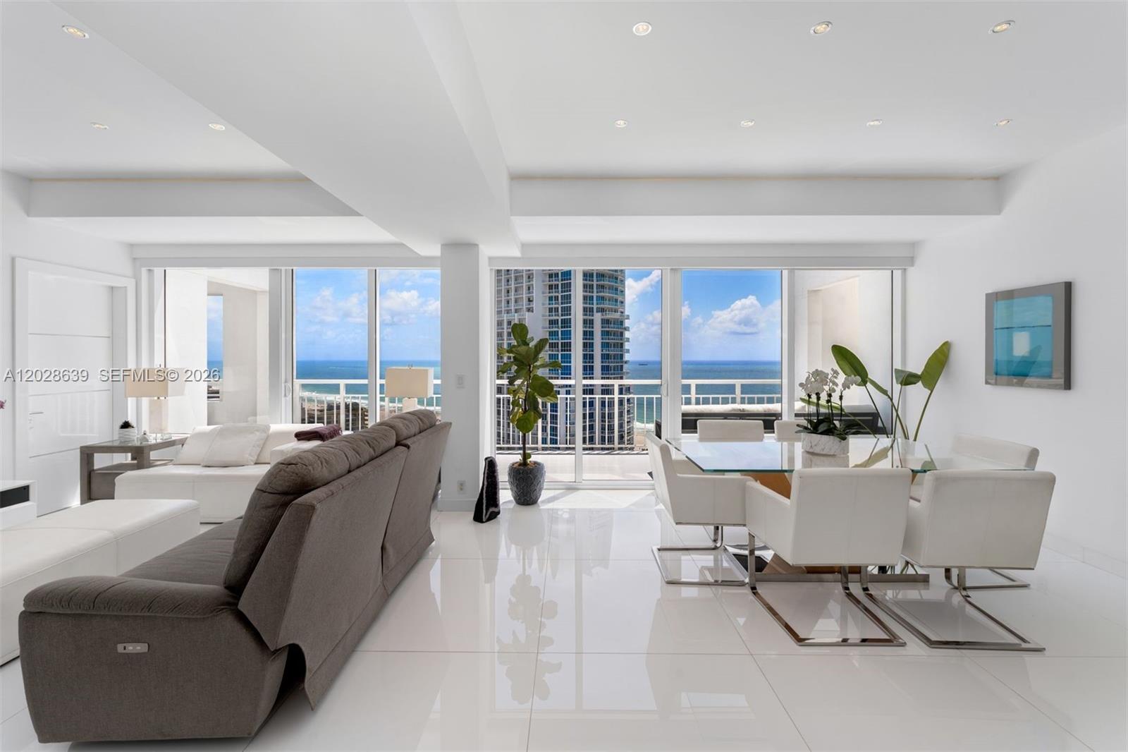 A bright living and dining area features white tile floors, modern furniture, and ocean views — 400 S Pointe Dr, Miami Beach FL 33139, MIAMI BEACH, FL