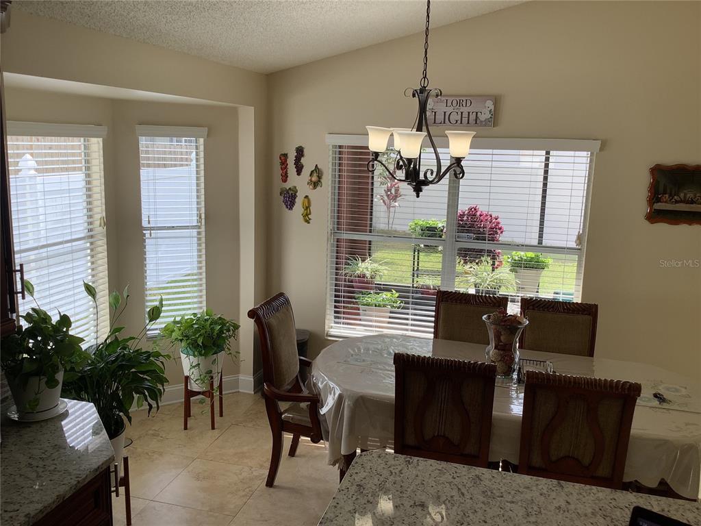 A dining area features a round table, wooden chairs, a chandelier, and large windows — 514 TREE SHORE DRIVE, ORLANDO, FL