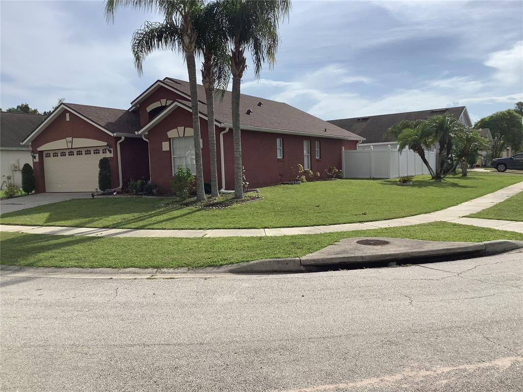 A red single-story house with a two-car garage and palm trees on a corner lot — 514 TREE SHORE DRIVE, ORLANDO, FL