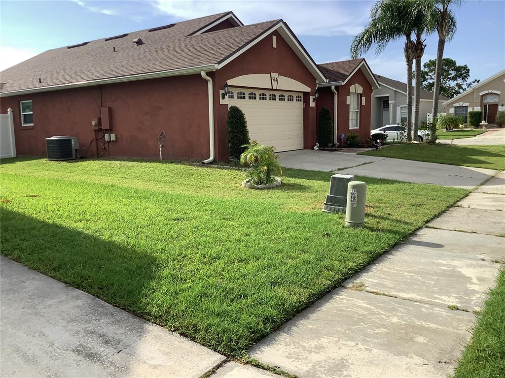 A red stucco house with a two-car garage and a green lawn under a blue sky — 514 TREE SHORE DRIVE, ORLANDO, FL