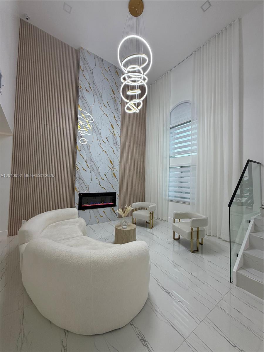 A modern living room features a marble fireplace, slatted wood walls, and a circular chandelier — 854 NW 132nd Ct, Miami FL 33182, MIAMI, FL