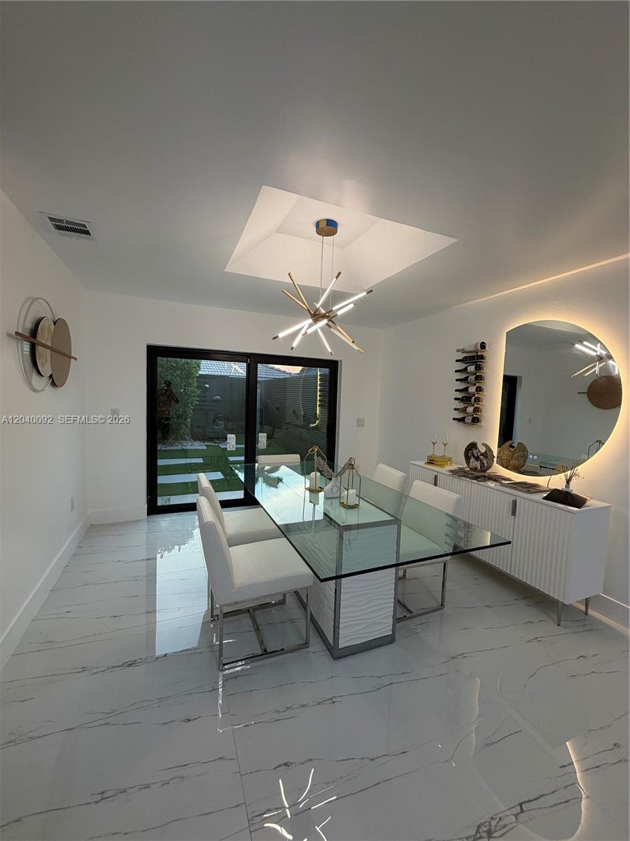A modern dining room features a glass table, white chairs, marble floors, and a circular mirror — 854 NW 132nd Ct, Miami FL 33182, MIAMI, FL