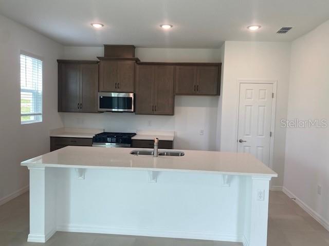 A kitchen features dark wood cabinets, a white island, and stainless steel appliances — 27412 BLACK KITE AVENUE, HOWEY IN THE HILLS, FL