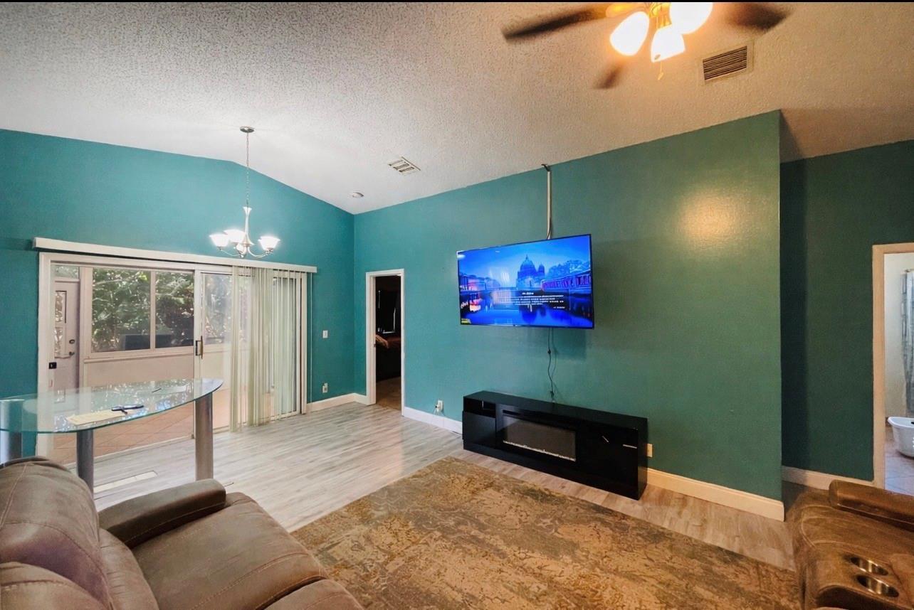 A living room features teal walls, a wall-mounted television, and a black media console — 244 Caribe Court, FL 33413, FL