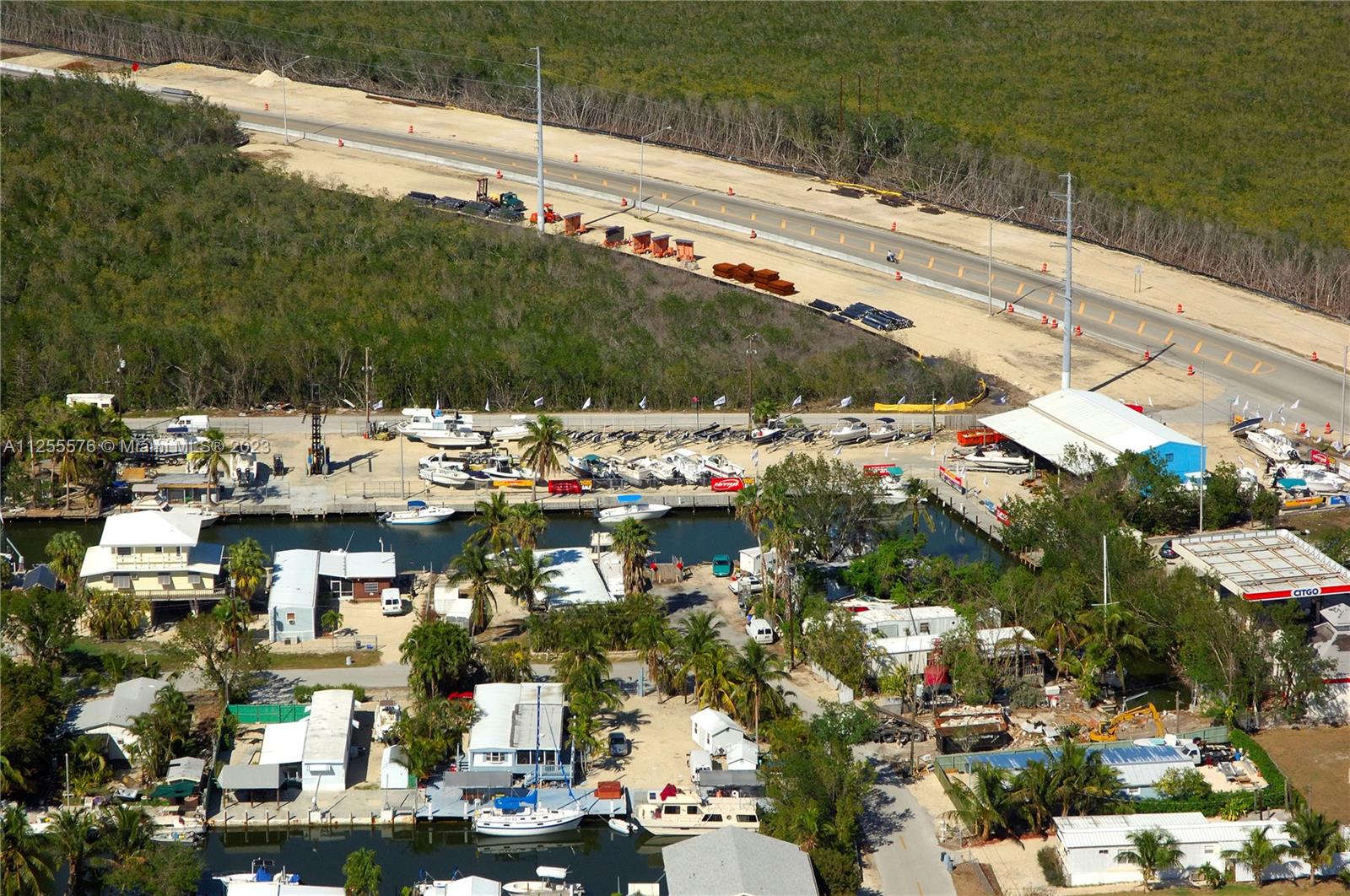 An aerial view shows a marina with docked boats, residential structures, and an adjacent highway — 10660 Summerland Dr, FL 33037, FL