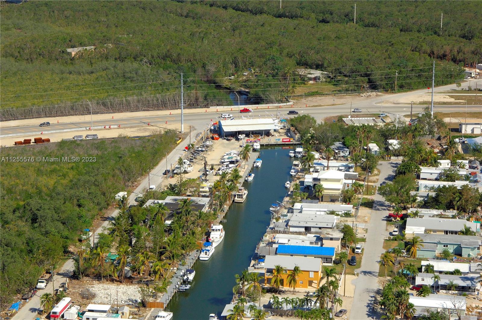 An aerial view shows a canal lined with boats, residential structures, and a nearby road — 10660 Summerland Dr, FL 33037, FL