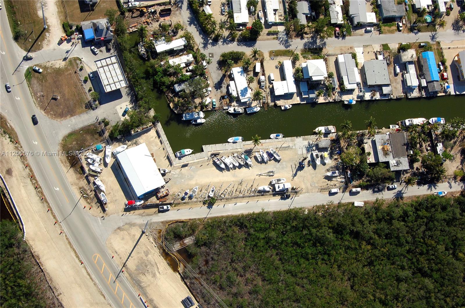 An aerial view shows a boat storage facility, a canal with docked boats, and nearby residences — 10660 Summerland Dr, FL 33037, FL