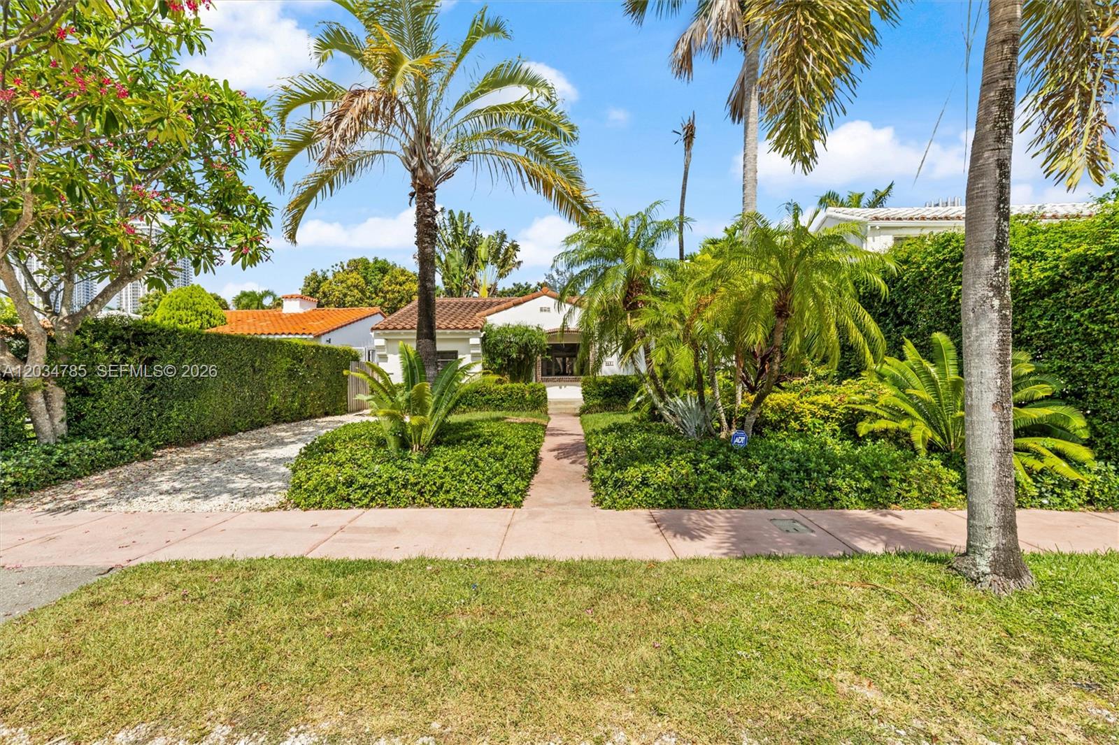 A single-story house with a tile roof is surrounded by lush landscaping and palm trees — 4531 Sheridan Ave, Miami Beach FL 33140, MIAMI BEACH, FL