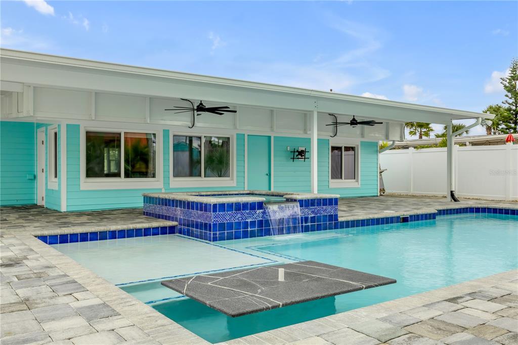 A turquoise house exterior features a swimming pool with a raised tiled spa and waterfall — 921 E 2ND AVENUE, NEW SMYRNA BEACH, FL