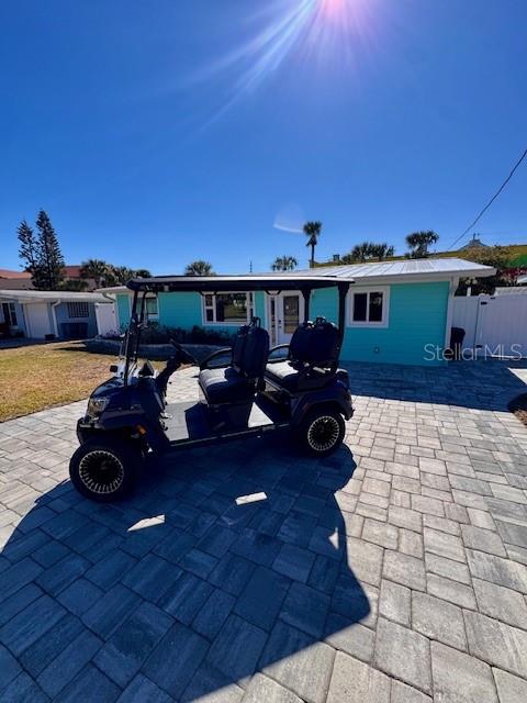 A dark golf cart is parked on a paved driveway in front of a teal house — 921 E 2ND AVENUE, NEW SMYRNA BEACH, FL