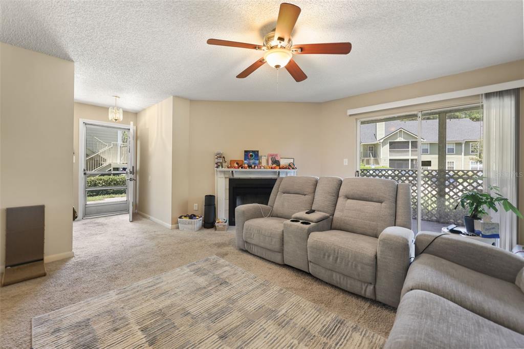 A living room features a fireplace, a ceiling fan, carpeted floors, and a sliding glass door — 3729 S LAKE ORLANDO PARKWAY UNIT 5, ORLANDO, FL