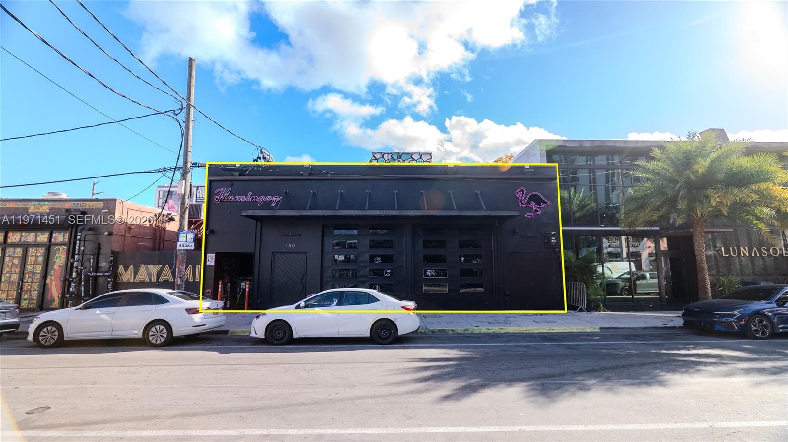 A black commercial building with a flamingo sign sits between two other structures — 150 NW 24th St, Miami FL 33127, MIAMI, FL