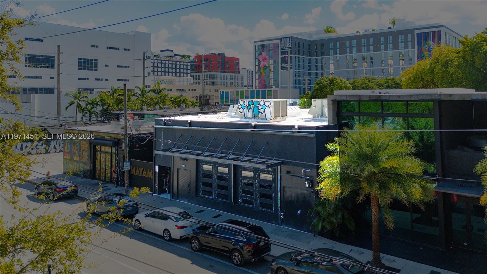 An exterior view of a black commercial building with street parking and surrounding urban architecture — 150 NW 24th St, Miami FL 33127, MIAMI, FL