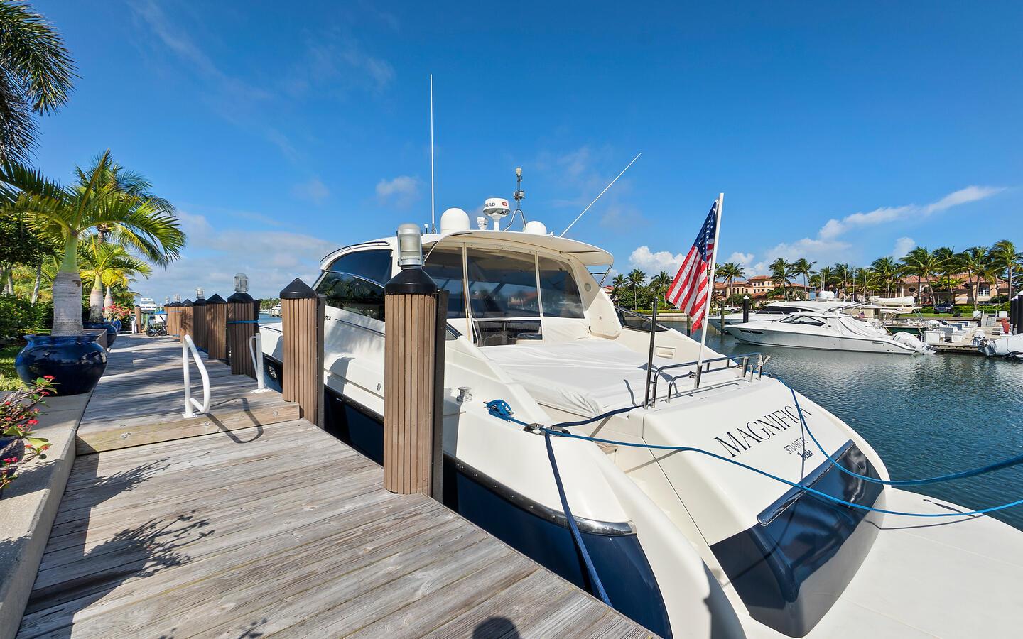 A white yacht named Magnifica is docked at a wooden pier under a blue sky — 6819 SE South Marina Way, Stuart FL 34996, STUART, FL