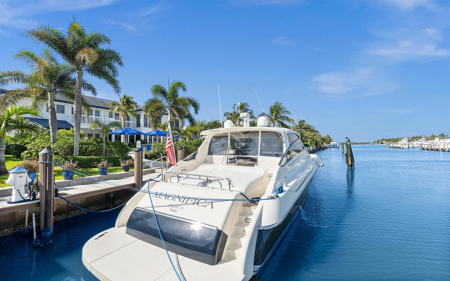A white yacht named Magnifica is docked at a canal next to a residential building — 6819 SE South Marina Way, Stuart FL 34996, STUART, FL