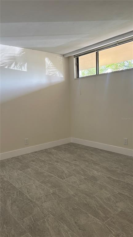 An empty room features light-colored walls, a window with blinds, and gray tile flooring — 2618 COVE CAY DRIVE UNIT 103, CLEARWATER, FL