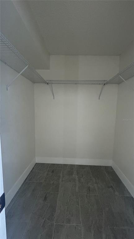A walk-in closet with white walls, wire shelving, and gray tile flooring — 2618 COVE CAY DRIVE UNIT 103, CLEARWATER, FL