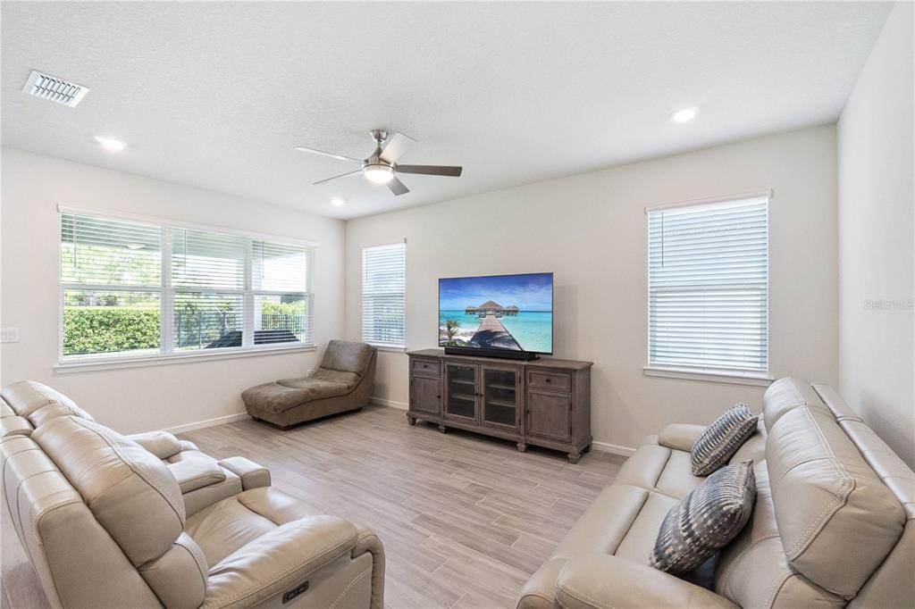 A living room features light wood-look tile flooring, a ceiling fan, and two leather sofas — 2691 RIVER CREEK LANE, ST CLOUD, FL