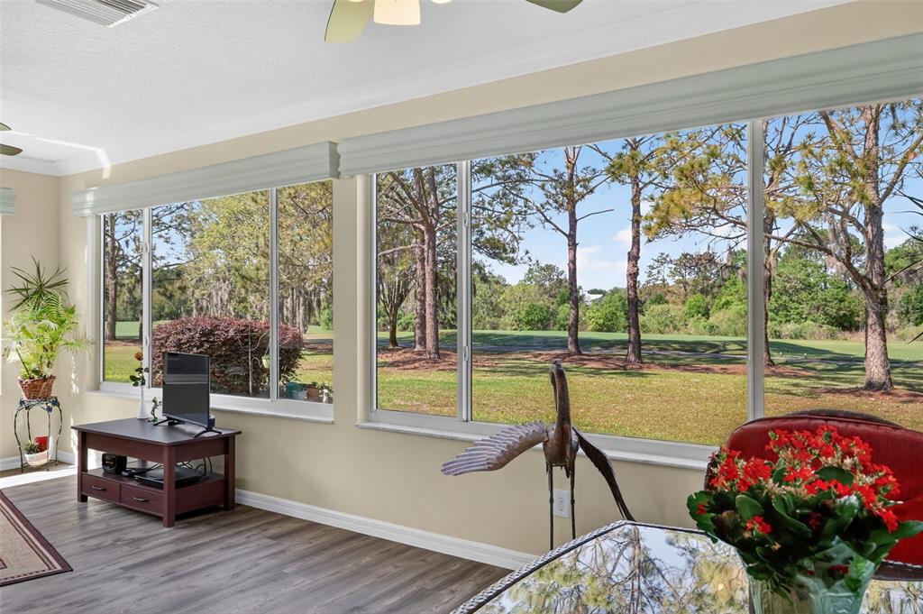 A sunroom with wood-look flooring, large windows, and a view of trees and a golf course — 416 CARRERA DRIVE, THE VILLAGES, FL
