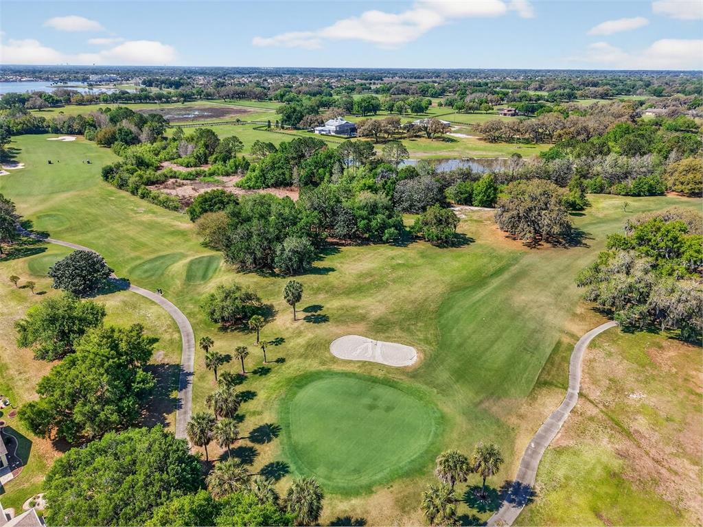 An aerial view of a golf course green with a sand bunker and surrounding trees — 416 CARRERA DRIVE, THE VILLAGES, FL