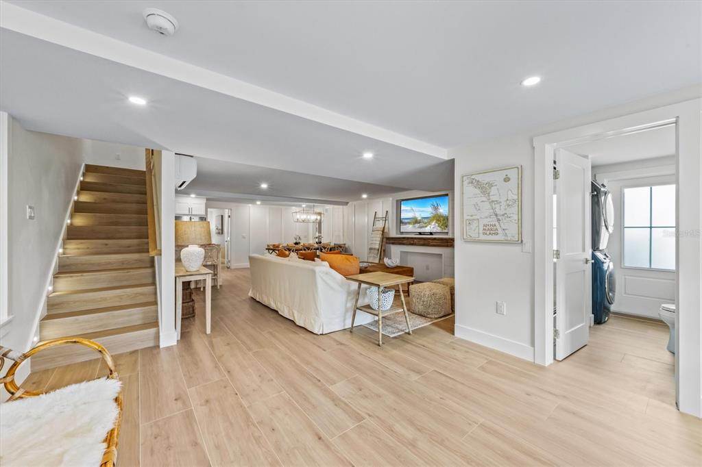A living room features light wood flooring, a staircase, and an adjacent laundry room — 112 CEDAR AVENUE, ANNA MARIA, FL