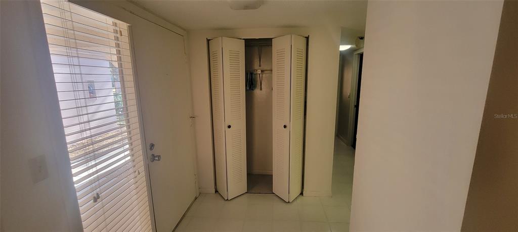 An entryway features a white door, a louvered closet, and light-colored tile flooring — 180 MAGNOLIA WOODS COURT UNIT 19A, DELTONA, FL