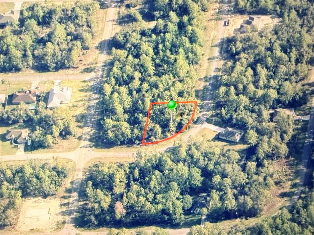 An aerial view shows a wooded, trapezoidal vacant lot outlined in red within a neighborhood — 6684 N WATERMAN DRIVE, DUNNELLON, FL