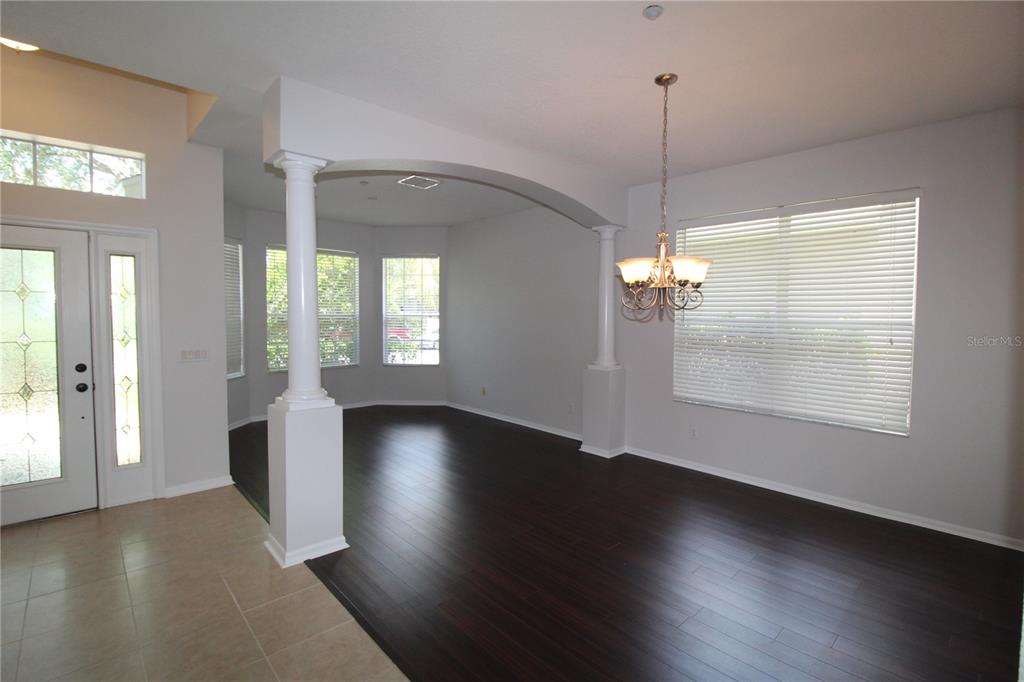 An interior view of a dining room featuring dark wood floors, columns, and a chandelier — 9885 LELAND DRIVE, ORLANDO, FL
