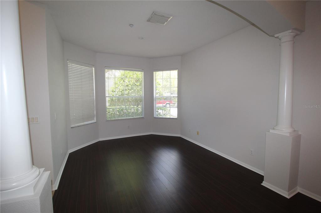 An empty room with dark wood flooring, white walls, and two decorative white columns — 9885 LELAND DRIVE, ORLANDO, FL