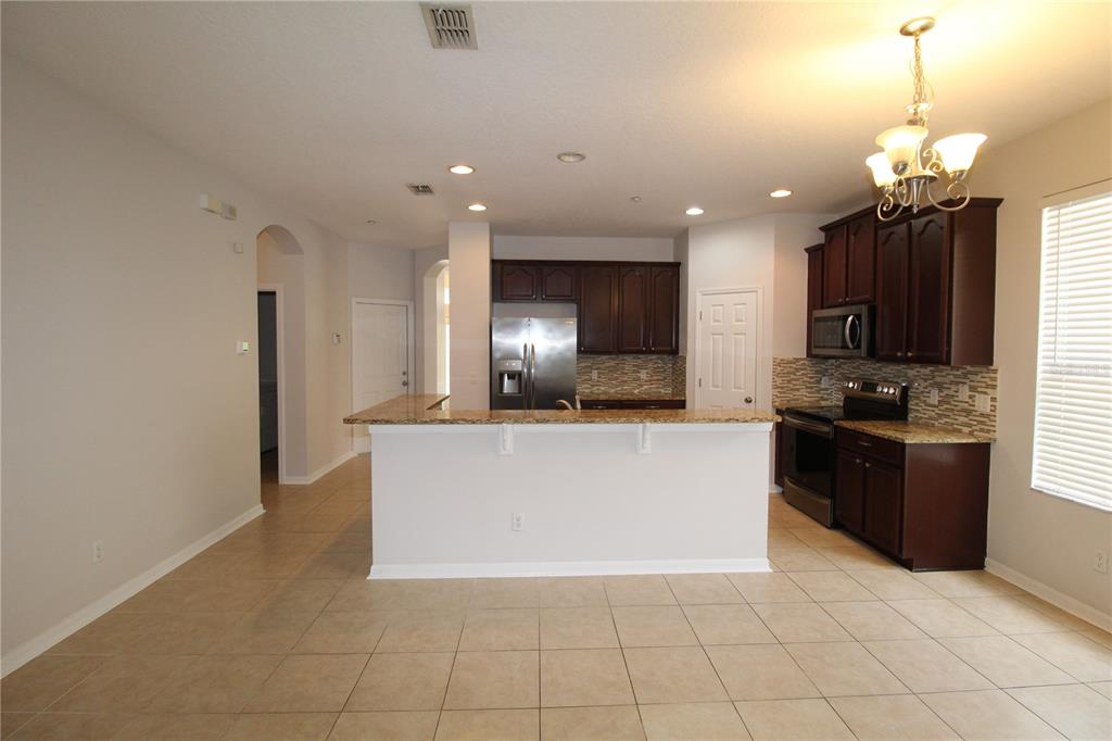 A kitchen with dark wood cabinets, granite countertops, stainless steel appliances, and tile flooring — 9885 LELAND DRIVE, ORLANDO, FL